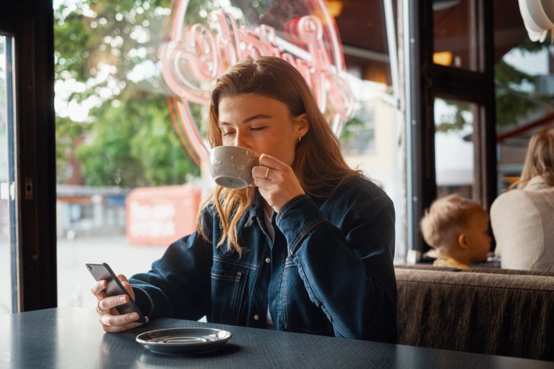 Woman drinking coffee and holding a mobile phone in a cafe